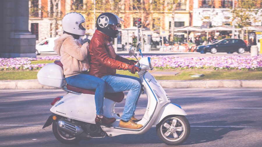 a couple riding a moped.