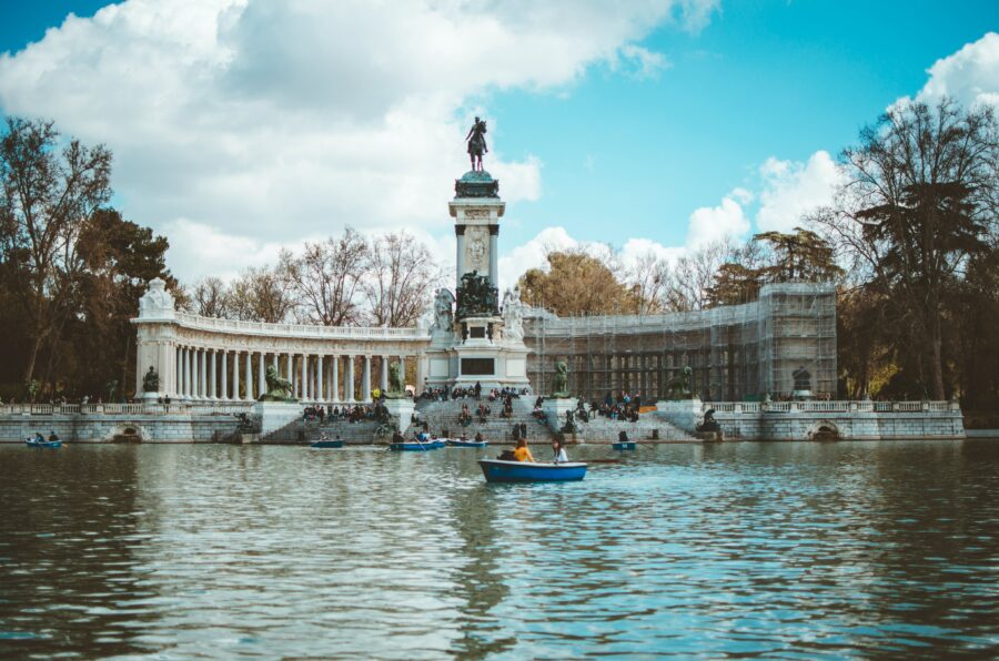 A boat in the water in front of a statue in Madrid.
