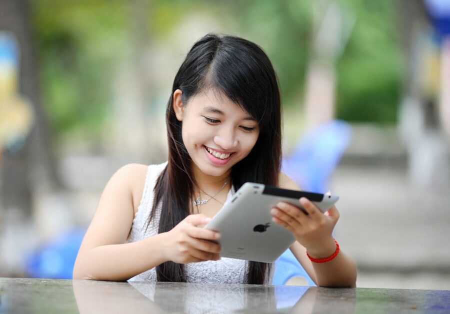 A smiling woman using an iPad after moving abroad for education